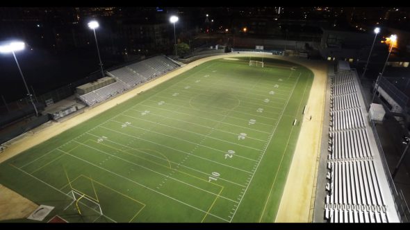 Aerial, man runs around football field at night Royalty Free Stock Drone Video Footage